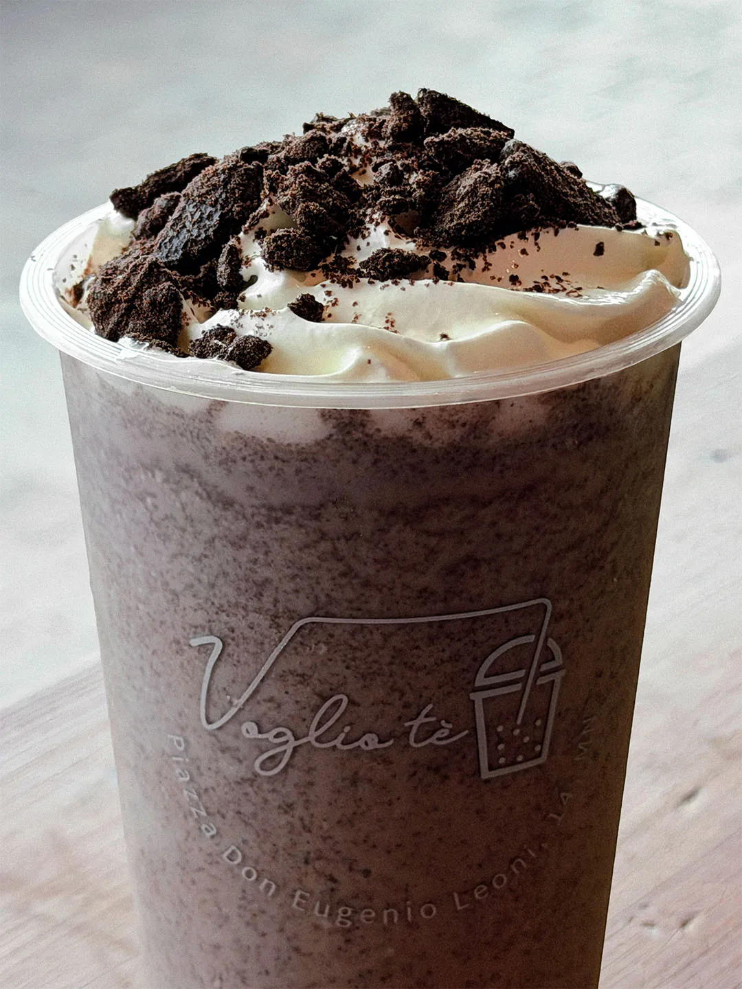 Oreo cream blended drink topped with whipped cream and crushed cookie, on a wooden table