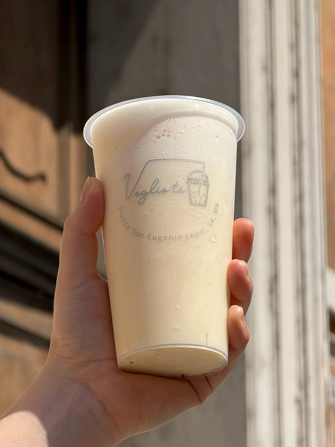 Mango slush held up in the sun in front of a stone doorway