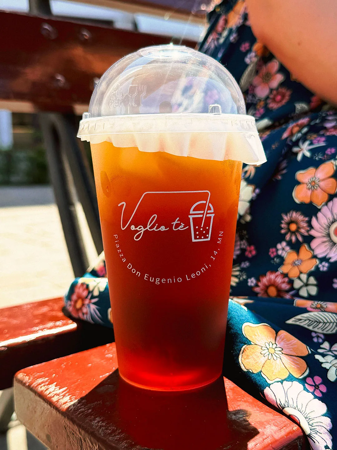 Osmanthus oolong tea under a dome lid, on a red bench next to a floral dress